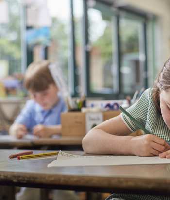 schoolgirl writing in classroom lesson in primary